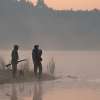 Two hunters are exploring the wild with a dog