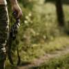 a man wear a hunting bib and hold a binoculars in the wild