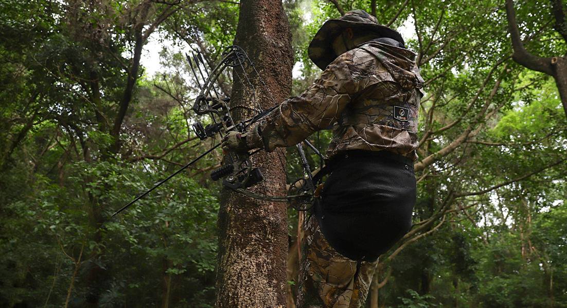 a hunter is using a saddle to hunt in the tree